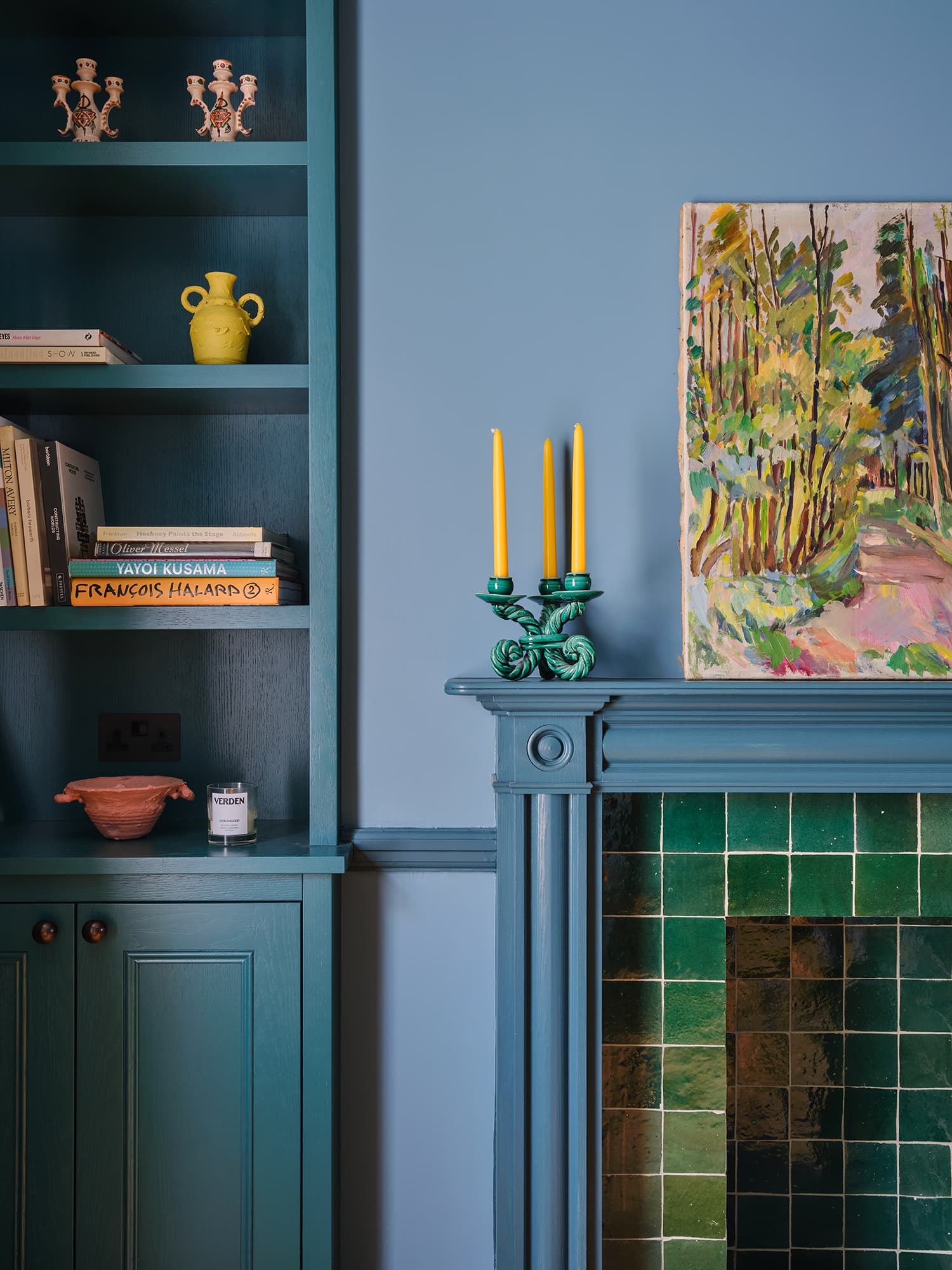 Nestled corner of a room with teal walls, a green tiled fireplace, and decorative elements.