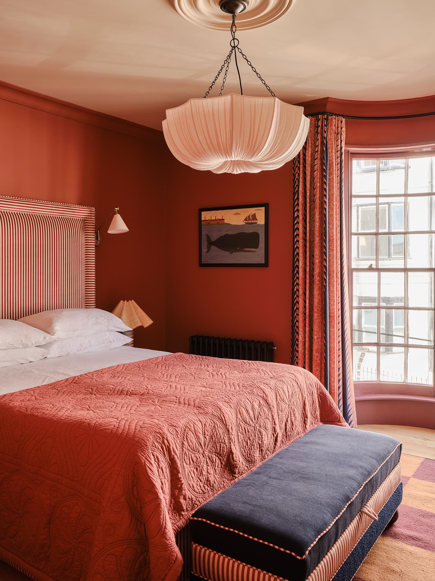 Bedroom with red walls, a bed, and a bench.