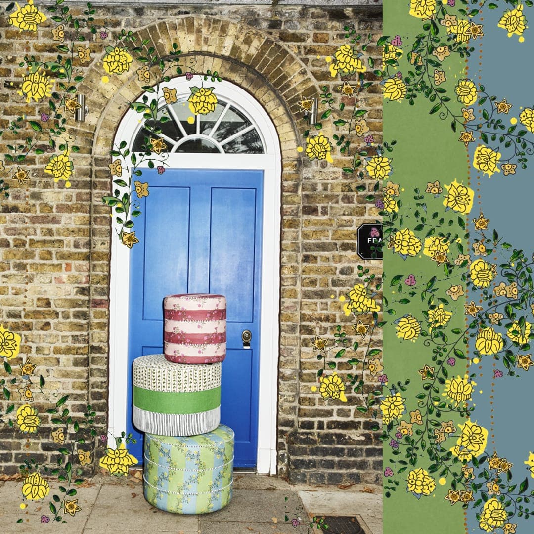 A decorative wallpaper or fabric pattern shown in a styled scene, featuring yellow flowers and green vines climbing around a blue front door set in a brick wall. A vertical strip on the right shows the pattern isolated with a blue sky background.